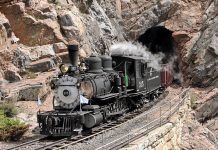 Steam engine train emerges from the Cumbres & Toltec Scenic Railroad's Rock Tunnel in New Mexico's Toltec Gorge.