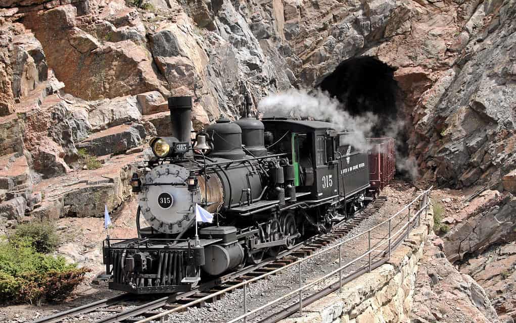 Steam engine train emerges from the Cumbres & Toltec Scenic Railroad's Rock Tunnel in New Mexico's Toltec Gorge. 